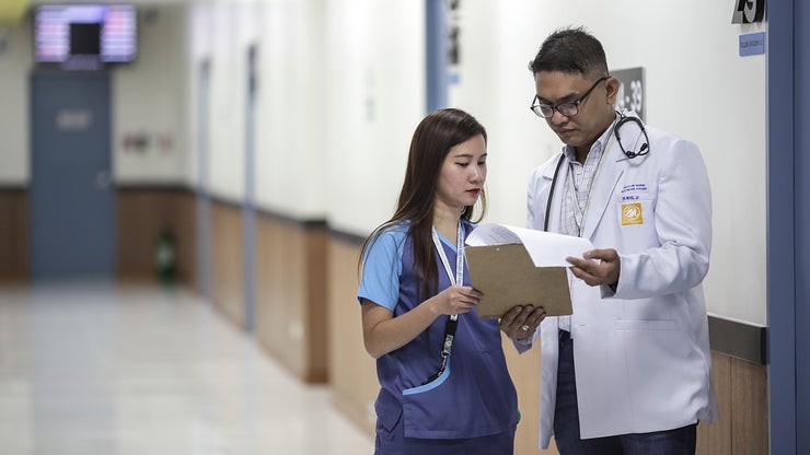 Doctor and assistant looking over paperwork in the corridor of a hospital