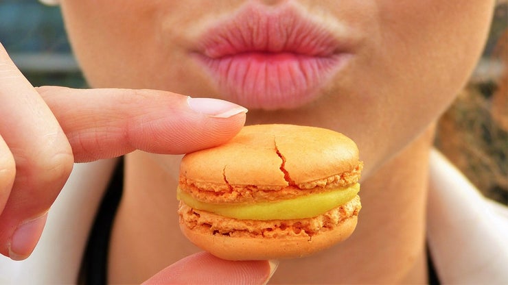 Woman holding a macaron in front of her face