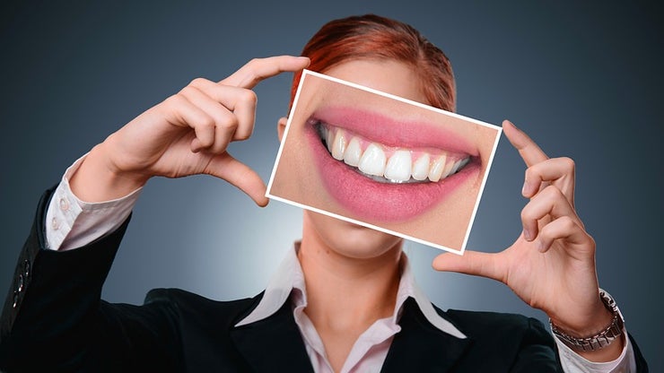 Woman holding a photo of teeth over her face